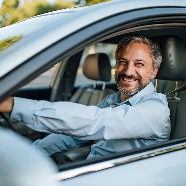 Platzhalterbild Mann grinst aus Auto